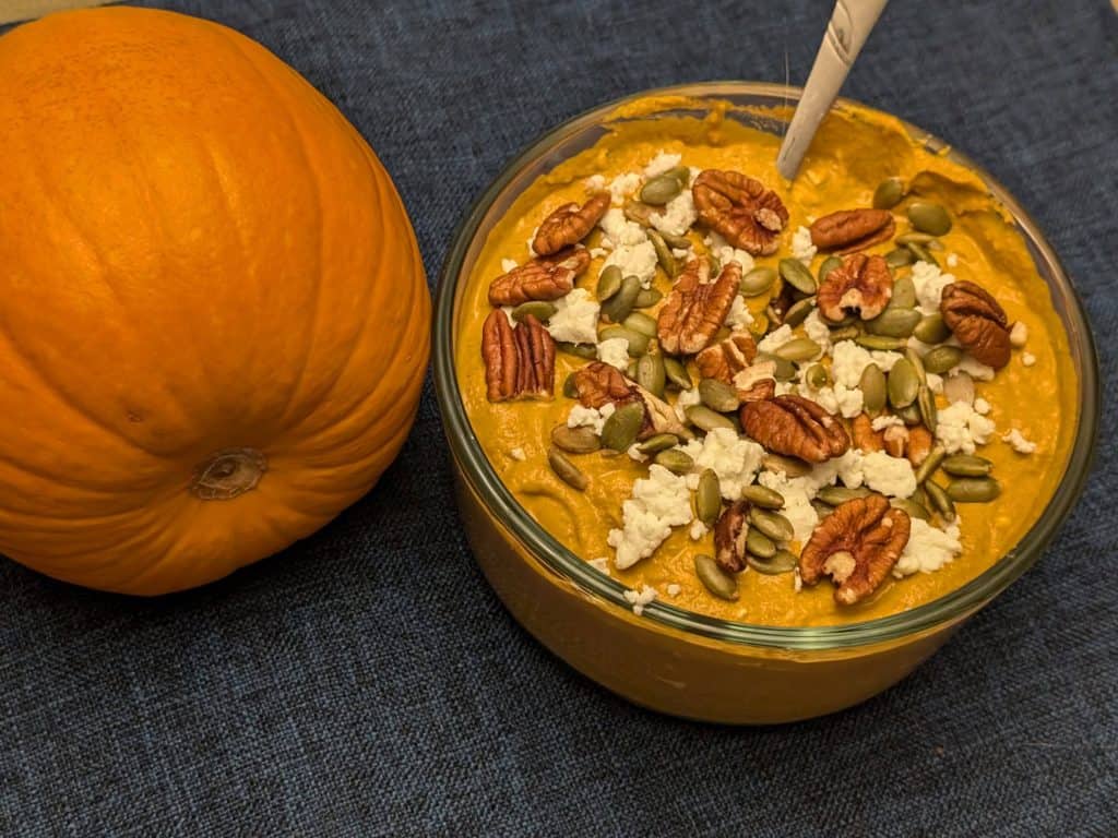 Spicy Pumpkin Pecan Dip in serving bowl next to a pumpkin