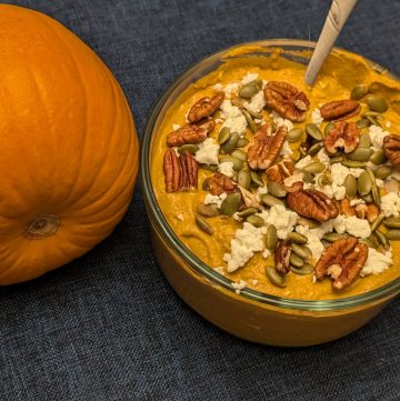 Spicy Pumpkin Pecan Dip in serving bowl next to a pumpkin