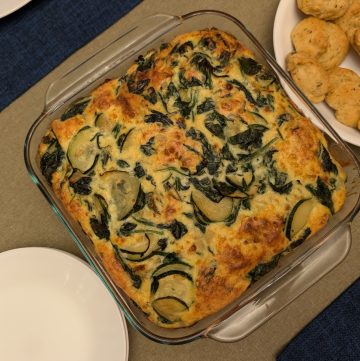 Zucchini Gouda Bake - Overhead In a casserole dish next to Savory Drop Biscuits