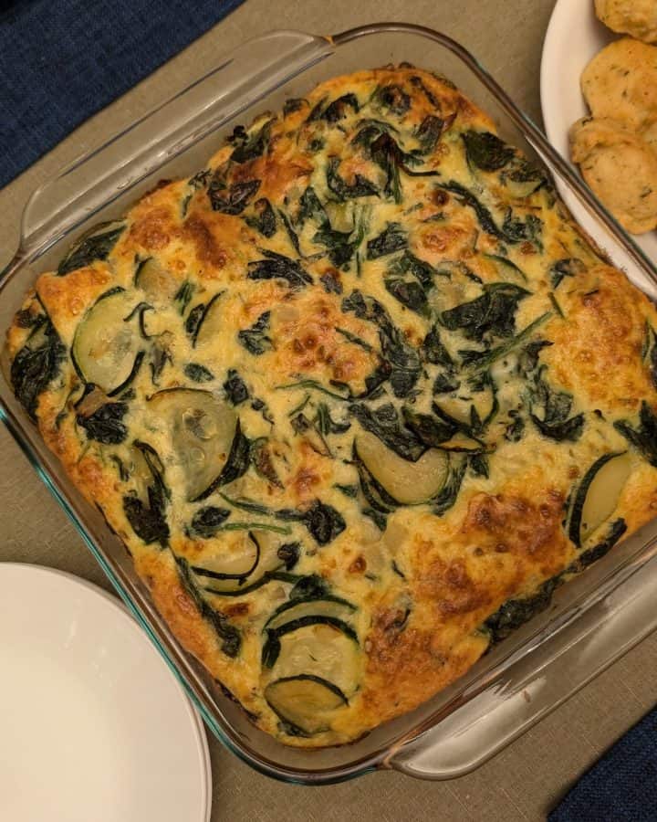 Zucchini Gouda Bake - Overhead In a casserole dish next to Savory Drop Biscuits