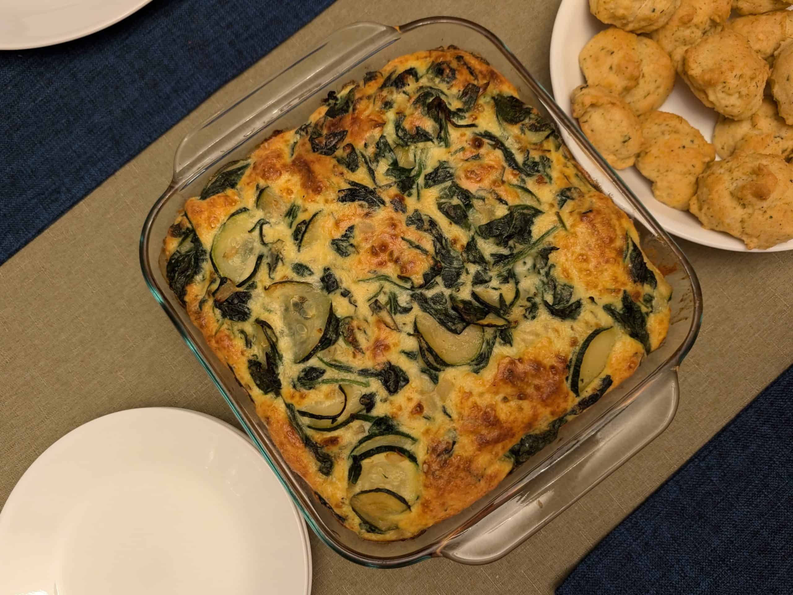 Zucchini Gouda Bake - Overhead In a casserole dish next to Savory Drop Biscuits