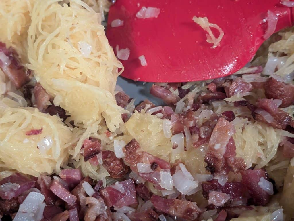 Adding cooked spaghetti squash to pan with bacon and onion for Spaghetti Squash Carbonara