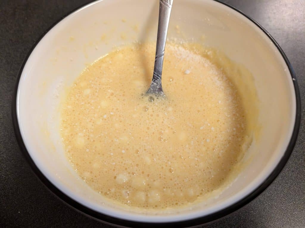 Bowl containing a mixture of beaten eggs and grated parmesan cheese