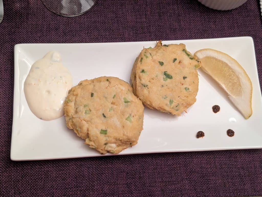 Keto Crab Cakes on a rectangular plate with Lemon-Garlic Aioli, 3 dots of Sriracha, and a wedge of lemon