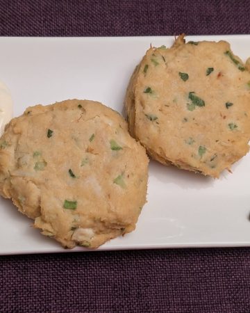 Keto Crab Cakes on a rectangular plate with Lemon-Garlic Aioli, 3 dots of Sriracha, and a wedge of lemon