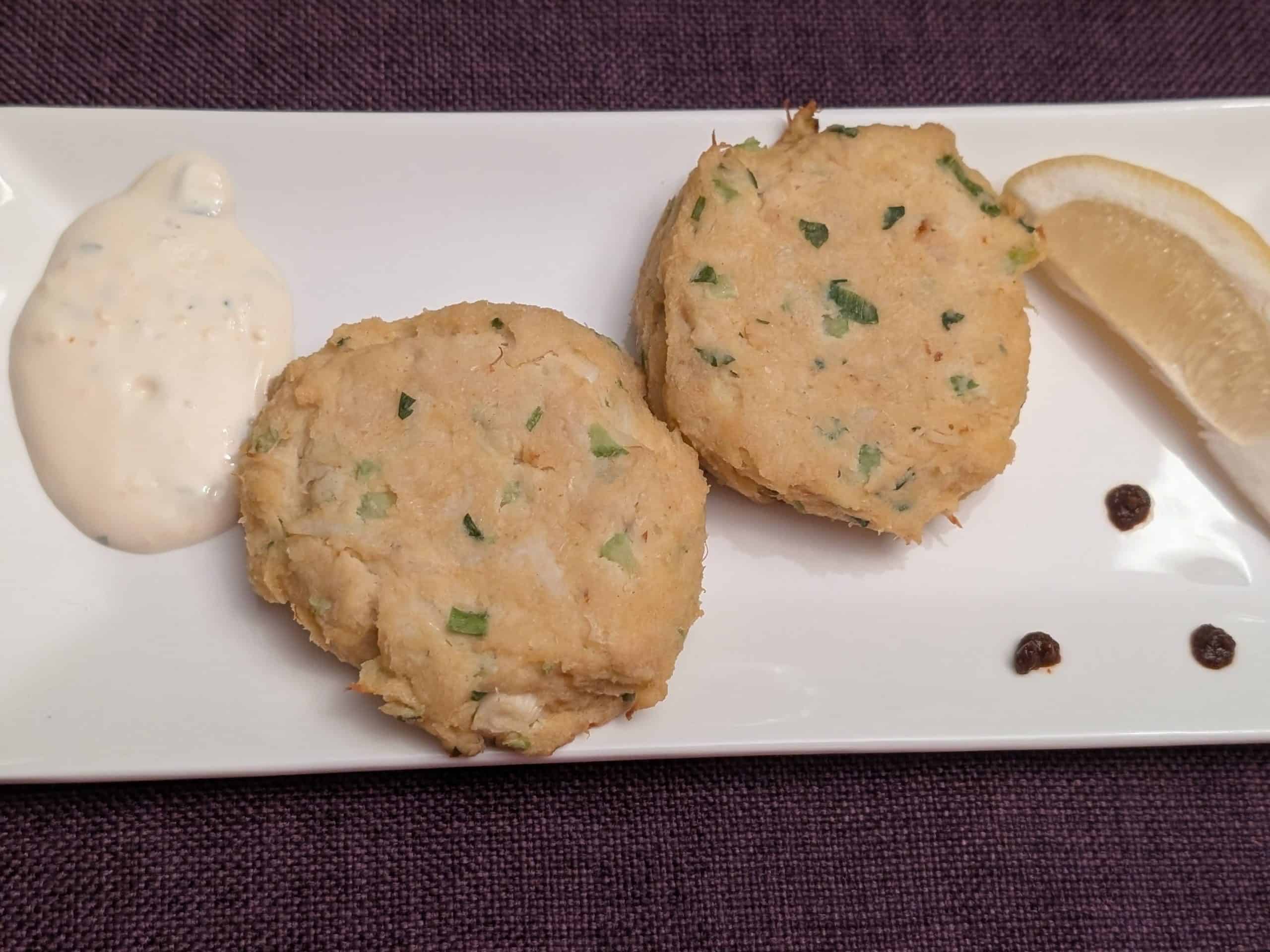 Keto Crab Cakes on a rectangular plate with Lemon-Garlic Aioli, 3 dots of Sriracha, and a wedge of lemon
