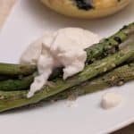 A close-up picture of Roasted Asparagus with Furikake and Burrata on a plate for service
