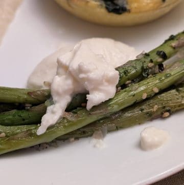 A close-up picture of Roasted Asparagus with Furikake and Burrata on a plate for service