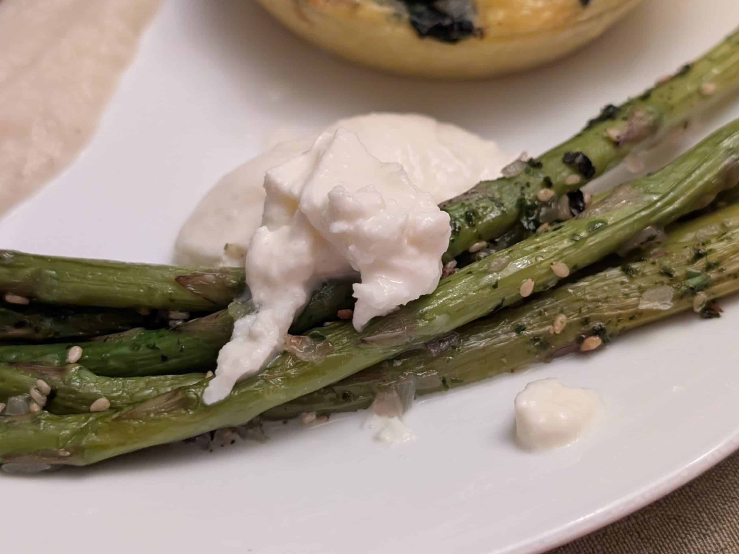 A close-up picture of Roasted Asparagus with Furikake and Burrata on a plate for service