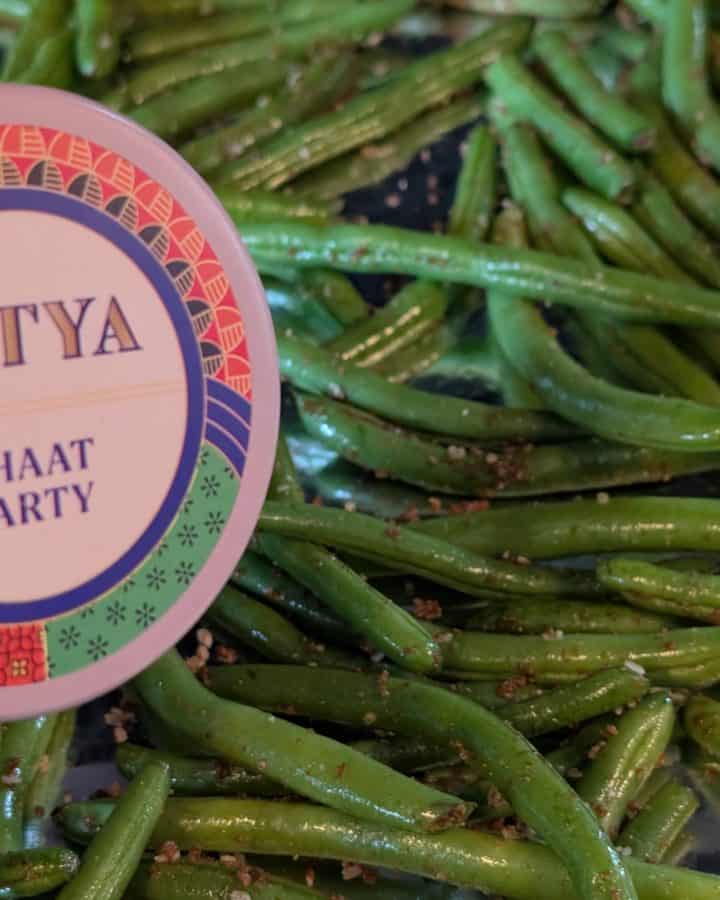 Raw green beans seasoned with Chaat Party Spice Blend on a sheet pan ready to roast