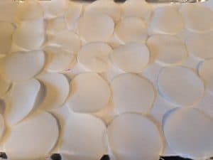 Turnip slices laid out on paper towel lined baking sheet to absorb any excess moisture