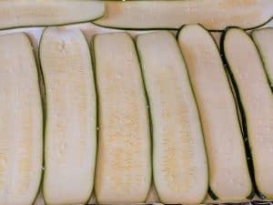 Raw zucchini planks sprinkled with kosher salt and laid out on a paper towel lined baking sheet to absorb excess moisture