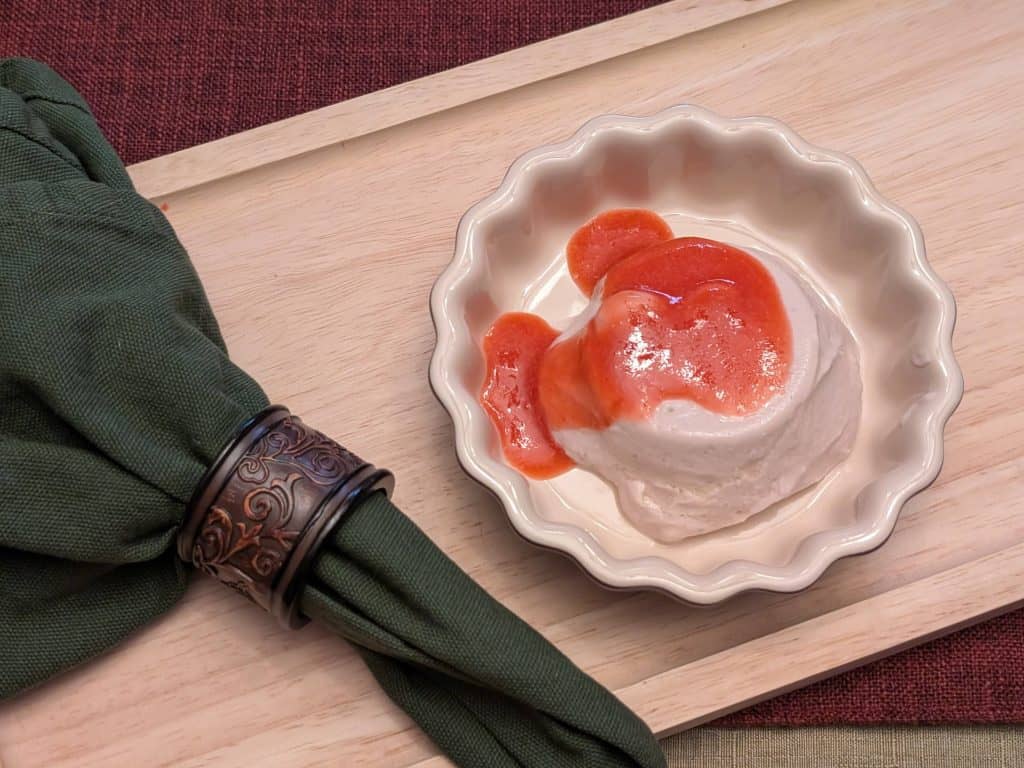 Strawberry Mango Sutra Panna Cotta in a serving dish topped with Strawberry Purée
