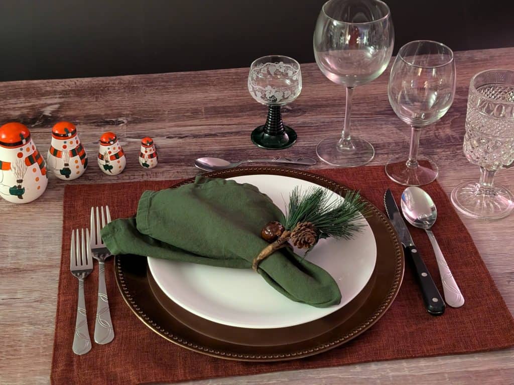 Holiday Dinner Party place setting with mini nesting snowmen and a pine cone decor napkin ring