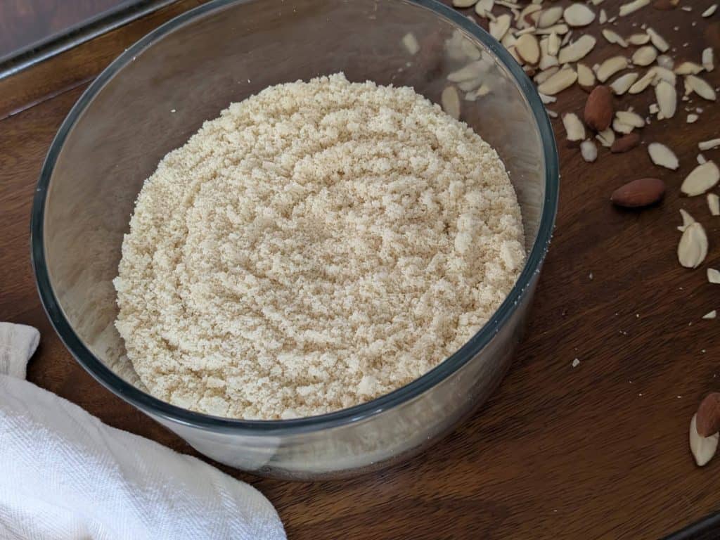 A bowl of Dinner Party Diaries Original Baking Mix on a wooden tray sprinkled with almonds