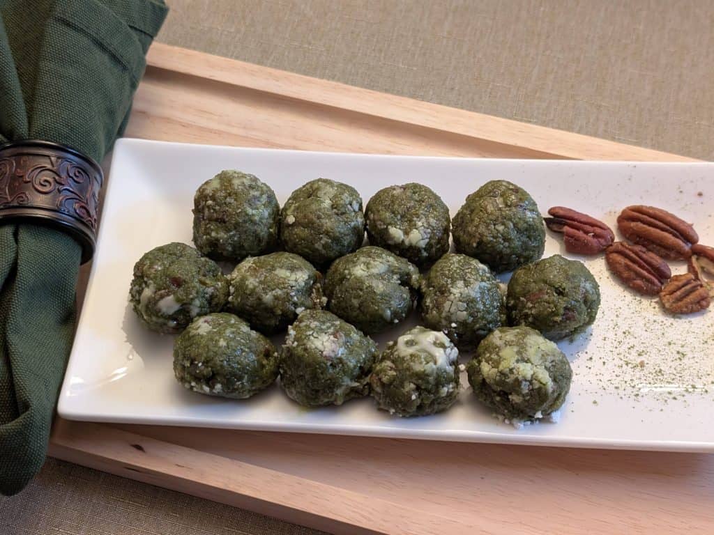 Matcha Nut Cookie Balls on a plate with pecans and sprinkles of matcha
