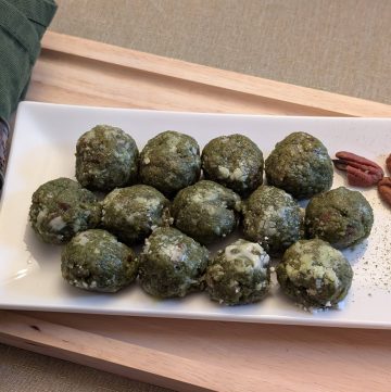 Matcha Nut Cookie Balls on a plate with pecans and sprinkles of matcha