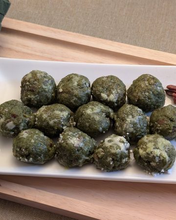 Matcha Nut Cookie Balls on a plate with pecans and sprinkles of matcha