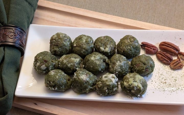 Matcha Nut Cookie Balls on a plate with pecans and sprinkles of matcha