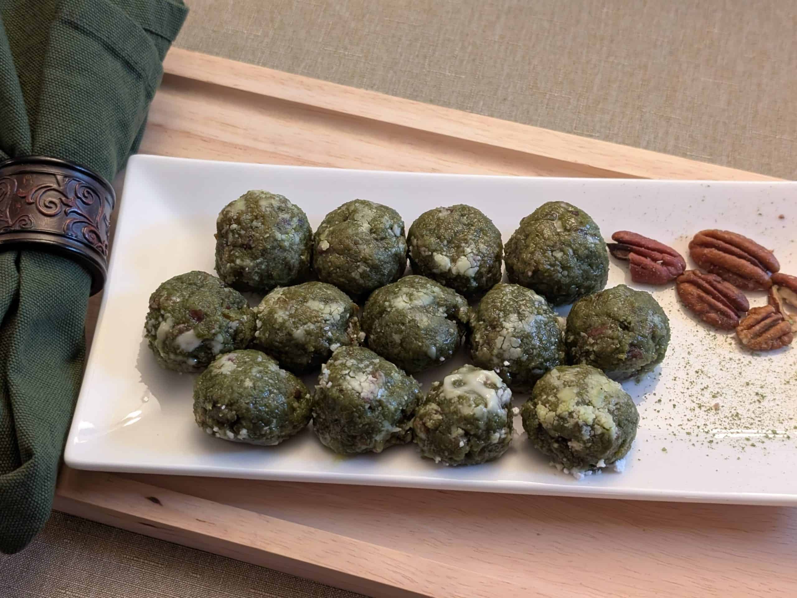 Matcha Nut Cookie Balls on a plate with pecans and sprinkles of matcha