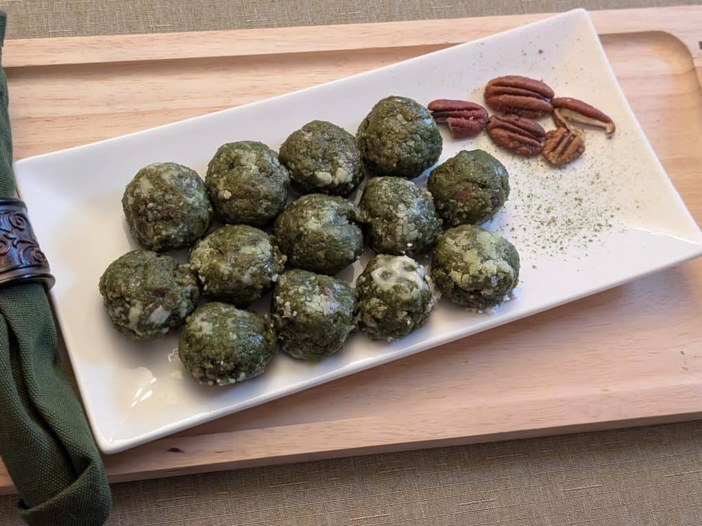 Matcha Nut Cookie Balls on a plate with pecans and sprinkles of matcha - close up
