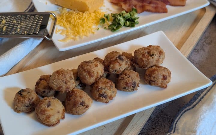Bacon Cheddar Jalapeno Biscuit Bites - Plated with sliced of cooked bacon, diced jalapenos, and a block of shredded cheddar cheese - Close up