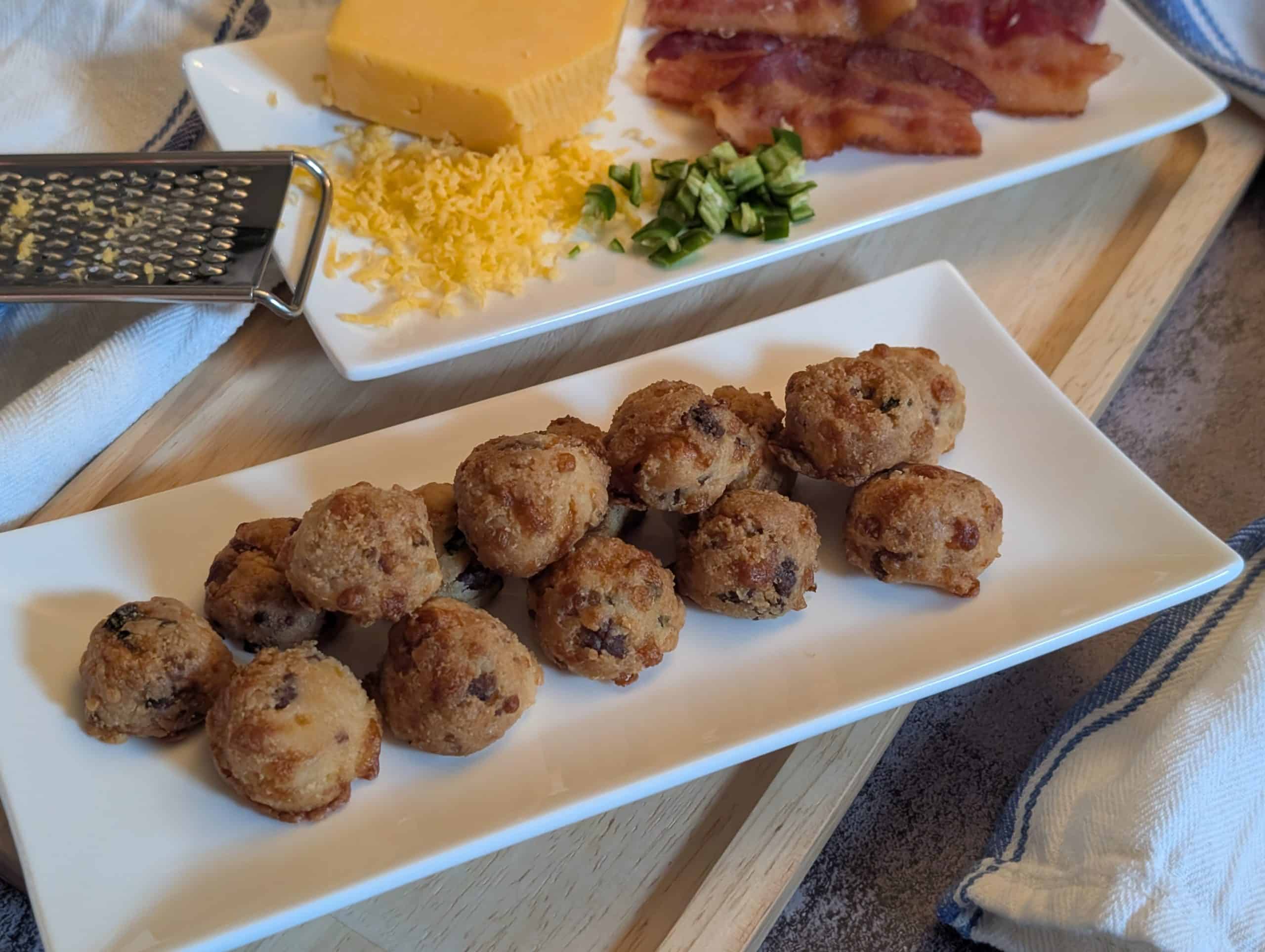 Bacon Cheddar Jalapeno Biscuit Bites - Plated with sliced of cooked bacon, diced jalapenos, and a block of shredded cheddar cheese - Close up