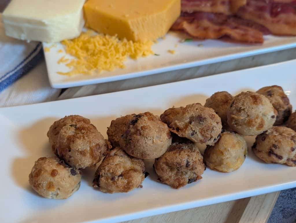 Cheesy Bacon Biscuit Bites - Plated with sliced of cooked bacon, a block of shredded cheddar cheese, and a block of shredded mozzarella cheese