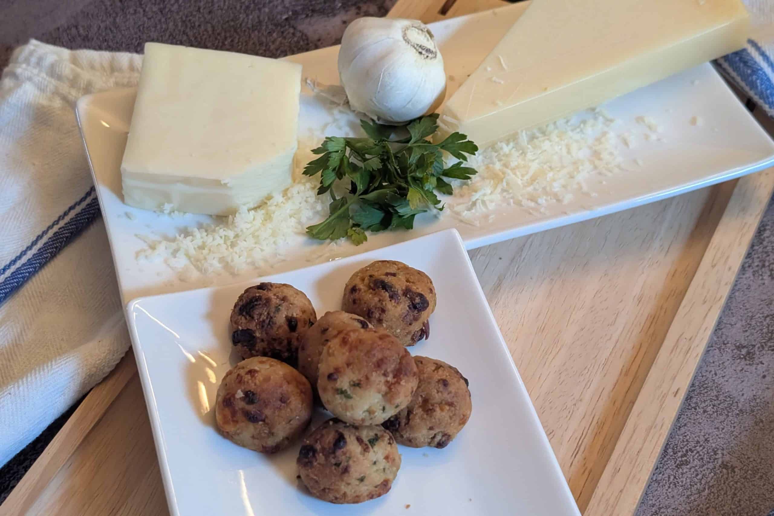 Cheesy Garlic Biscuit Bites - Plated with a block of shredded parmesan cheese, a block of shredded mozzarella cheese, a head of garlic, and fresh parsley